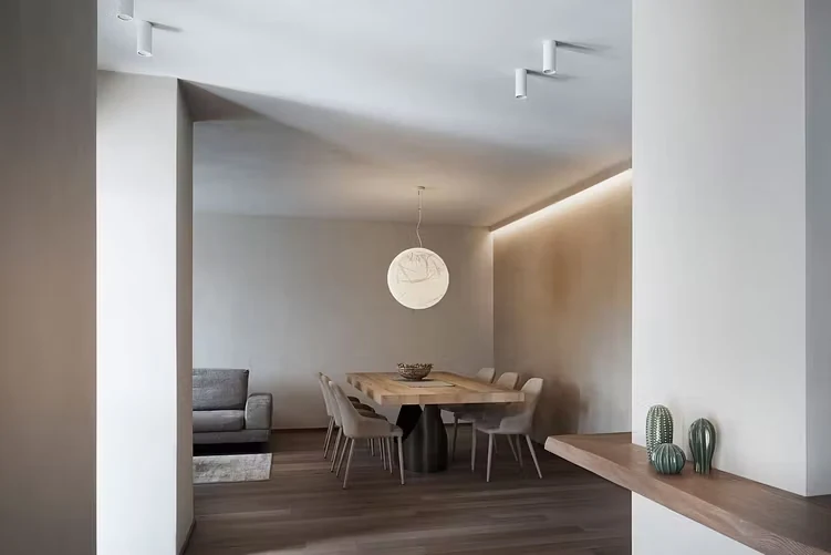 Salle à manger épurée, mur en enduit terre crue sable éclairé en corniche, ambiance minimaliste