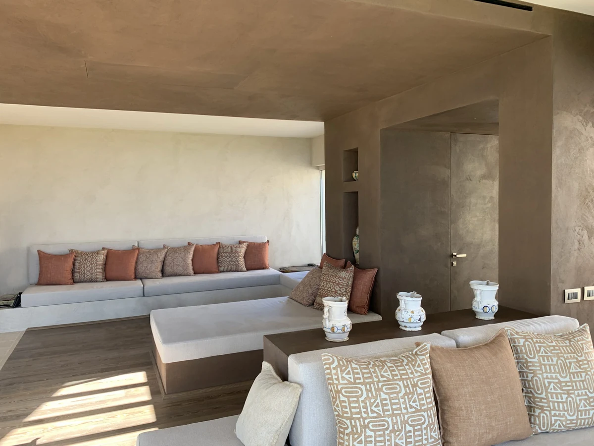 Séjour méditerranéen, murs et plafond en enduit terre crue TerraSilk teinte Zenzero, banquettes et coussins terracotta