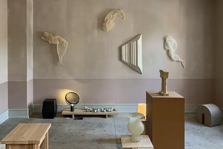 Galerie aux murs en enduit terre crue rose poudré, sculptures murales et socles, ambiance feutrée