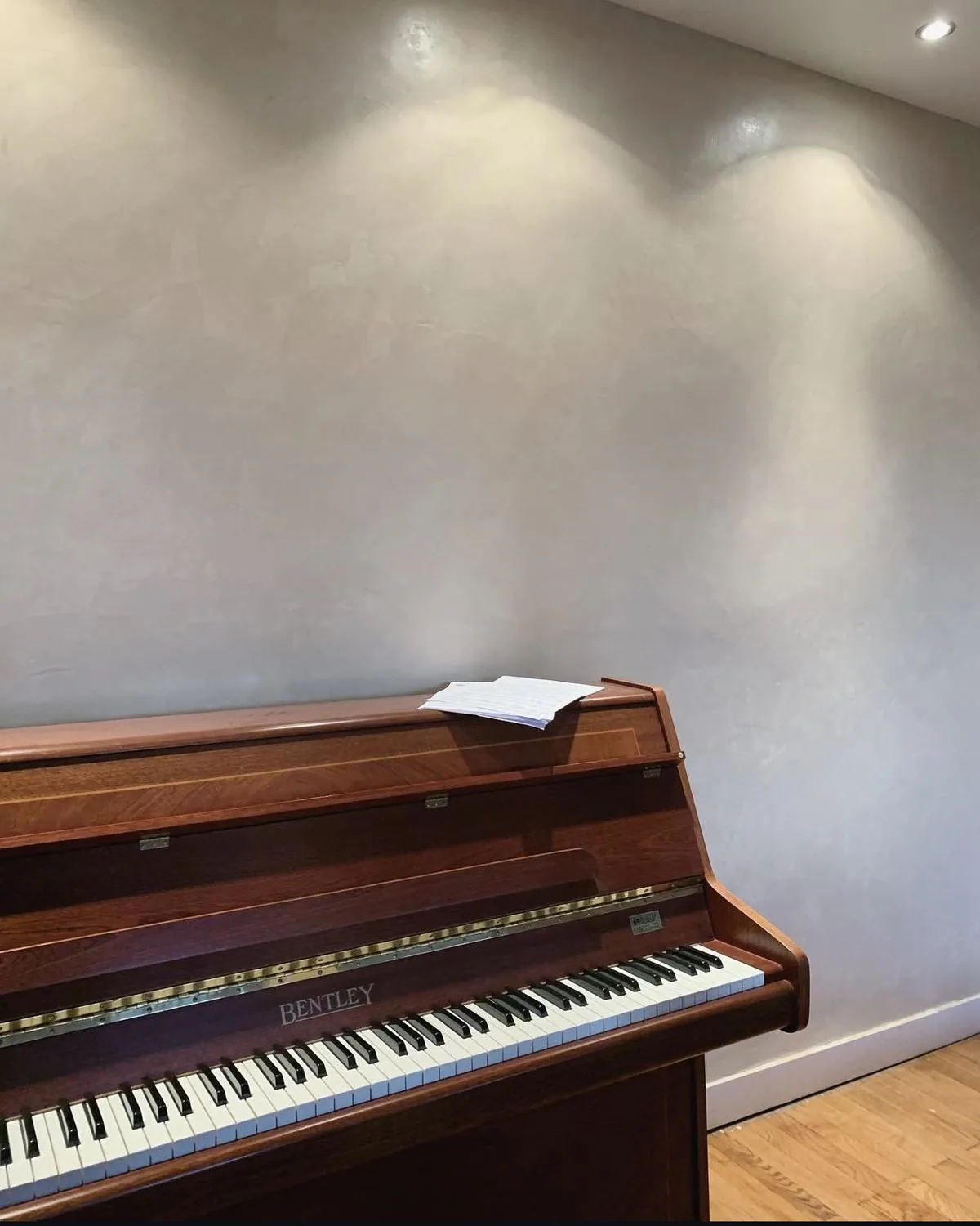 Piano droit devant un mur en enduit à la chaux gris perle