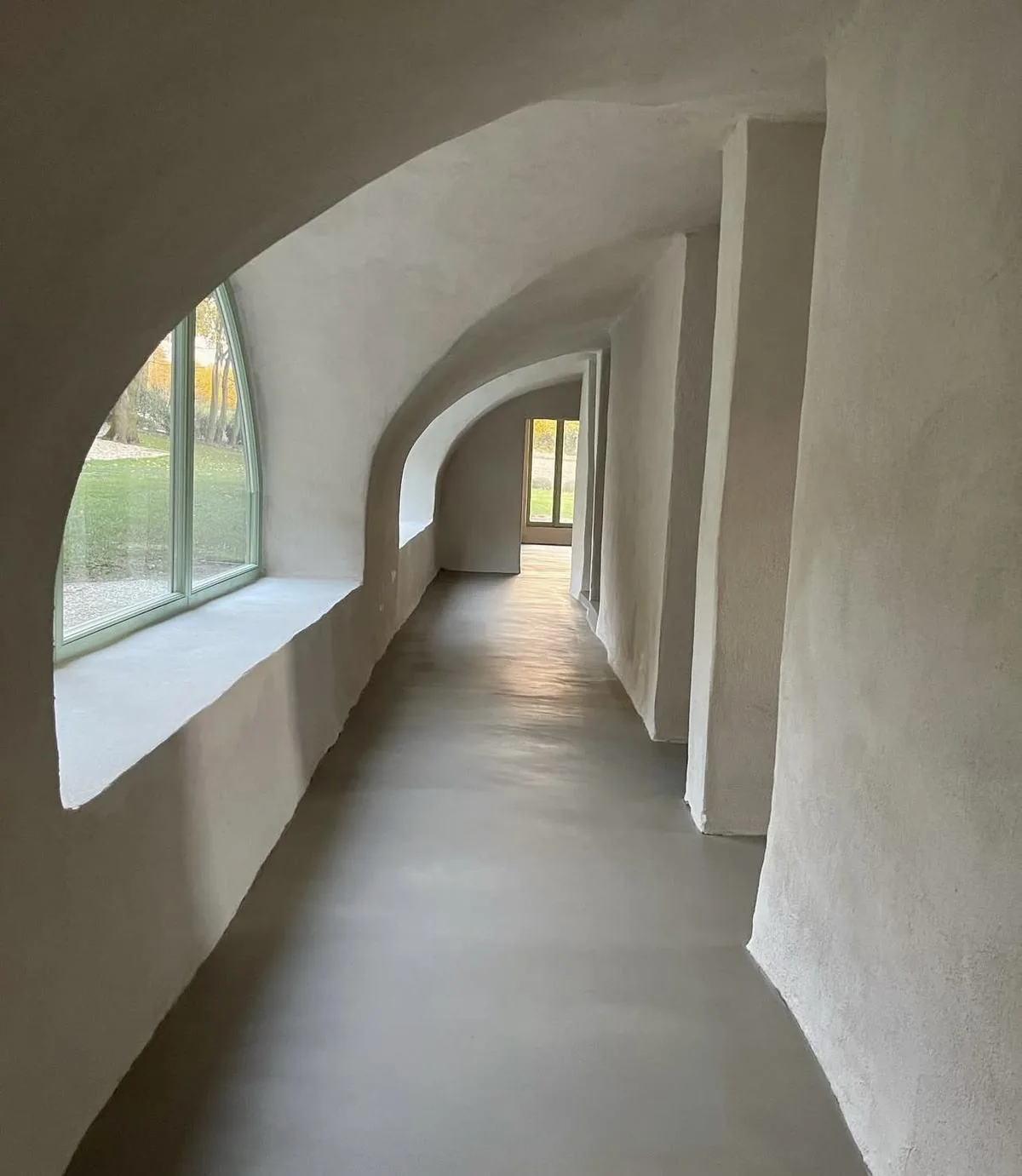 Couloir voûté aux murs et au sol en enduit à la chaux blanc