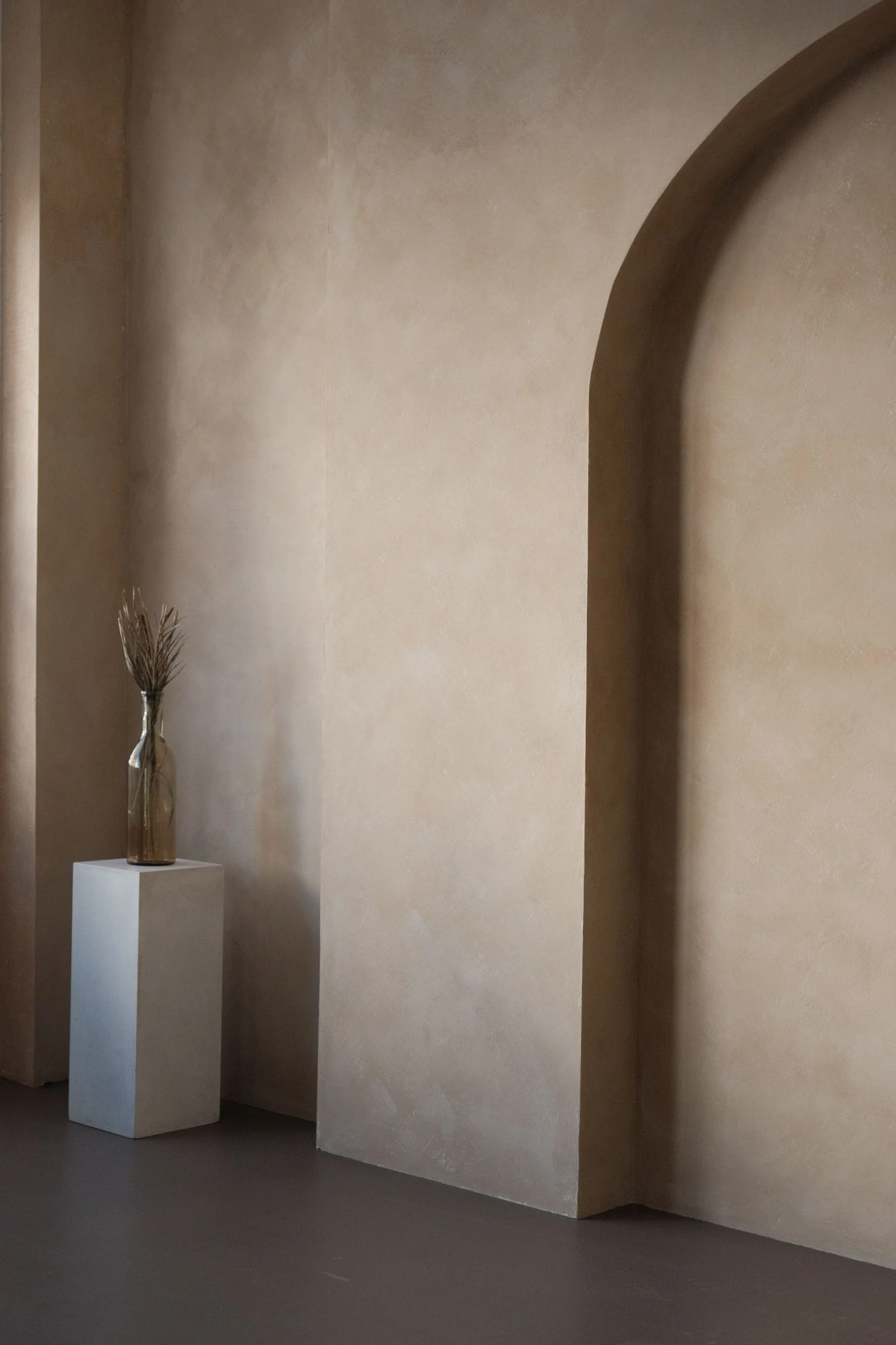 Mur en enduit à la chaux traditionnelle, patine beige nuancée autour d'une arche maçonnée