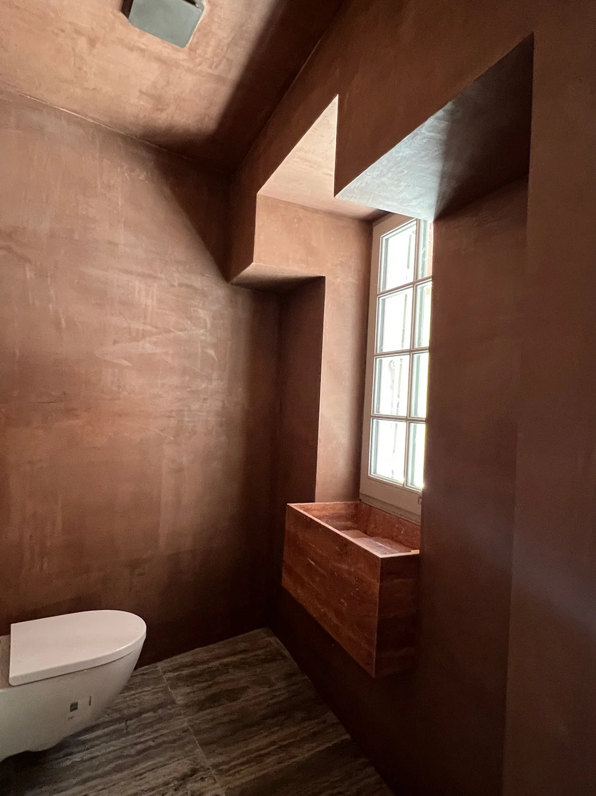 Petite pièce en enduit d'argile terracotta, intimité chaleureuse